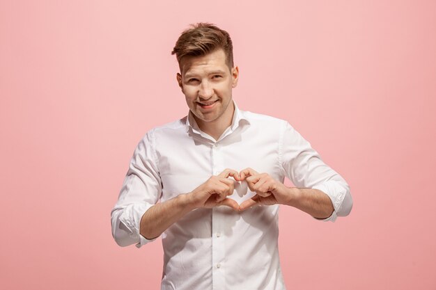 Happy business man standing and smiling against pink wall.