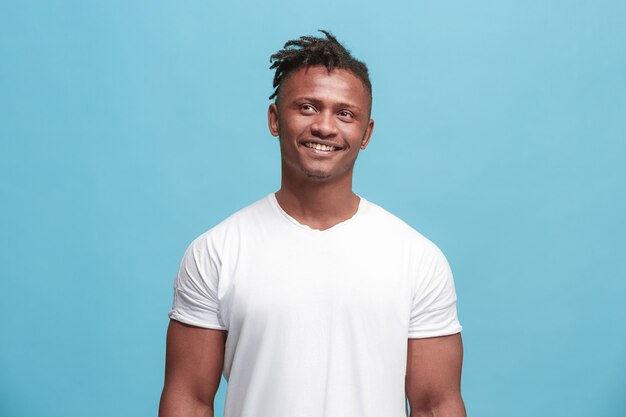 Happy business man standing and smiling isolated on blue studio background. African American male half-length portrait. Young emotional man. The human emotions, facial expression concept. Front view.