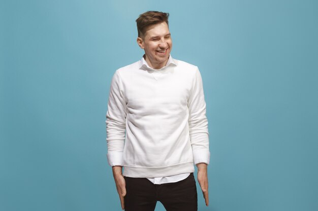 Happy business man standing and smiling isolated on blue studio background. Beautiful male half-length portrait. Young emotional man. The human emotions, facial expression concept. Front view.