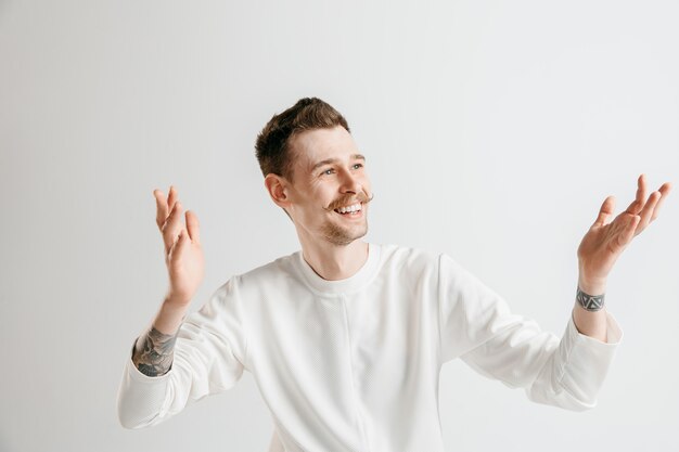 Happy business man standing, smiling isolated on gray studio background. Beautiful male half-length portrait. Young satisfy man. Human emotions, facial expression concept.