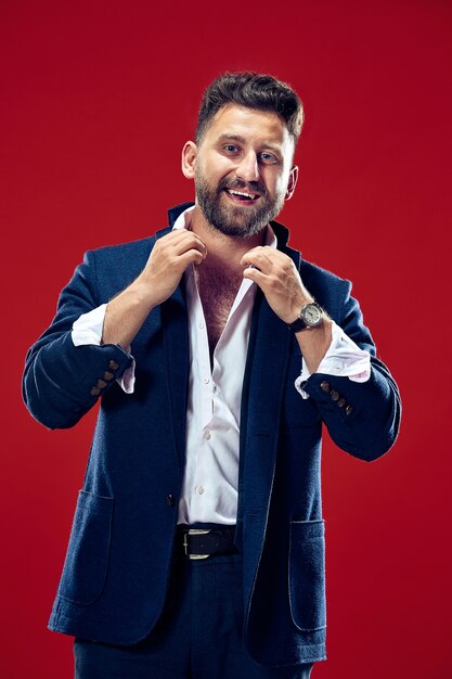 Happy business man standing and smiling isolated on red studio wall