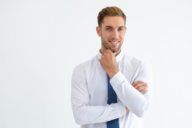 Happy business man touching chin and looking at camera