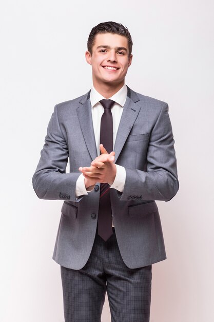 Happy business man wearing grey suit standing isolated on white wall