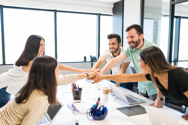 Foto gratuita uomini d'affari felici che celebrano il successo mentre impilano le mani nella riunione motivazionale in ufficio