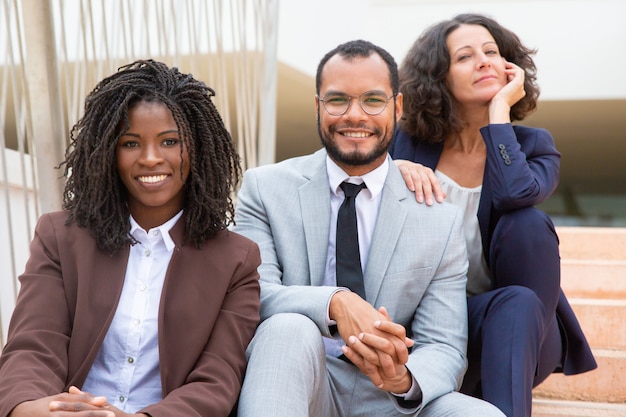 Free photo happy business people sitting on steps