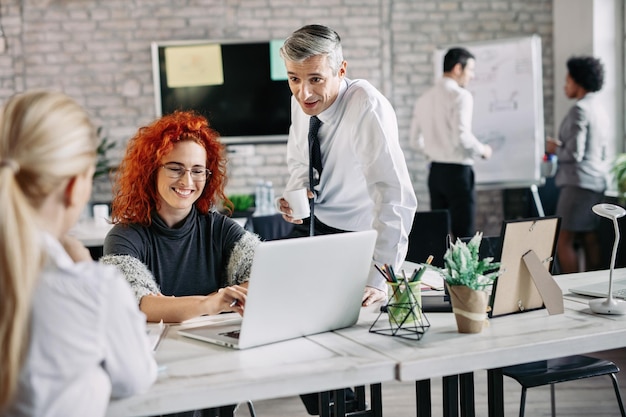 Uomini d'affari felici che parlano tra loro mentre lavorano in ufficio