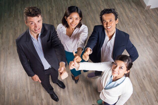 Счастливый бизнес команда показывает палец вверх в зале