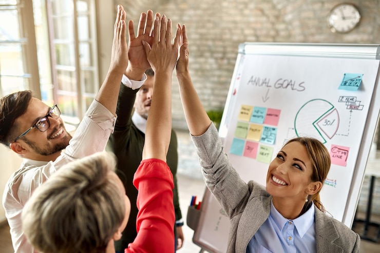Free Photo happy business team with raised hands celebrating their success in the office