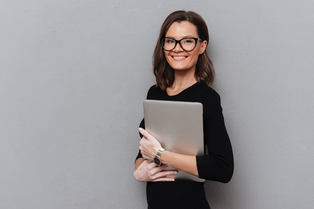 Happy business woman in eyeglasses holding tablet computer