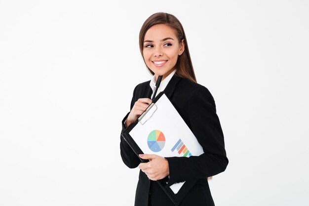 Happy business woman holding clipboard. Looking aside.