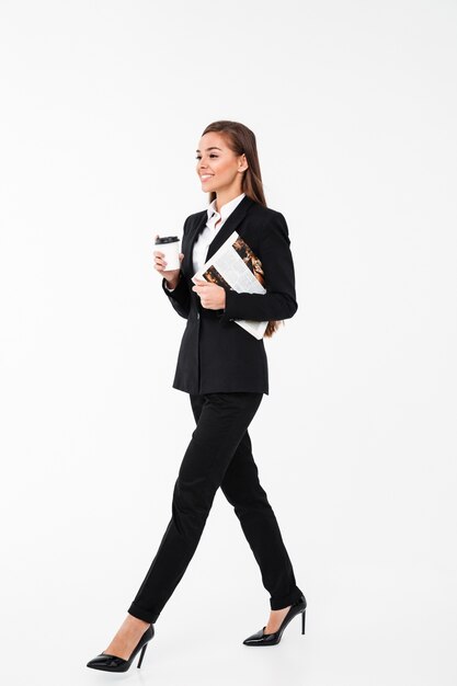 Happy business woman holding newspaper drinking coffee.