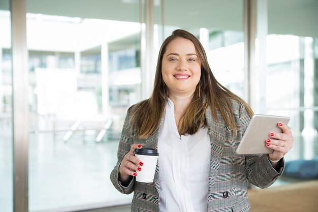Счастливая бизнес-леди держа таблетку и кофе outdoors