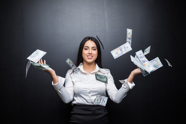 Foto gratuita donna d'affari felice sotto una pioggia di soldi fatta di dollari isolati sul muro nero