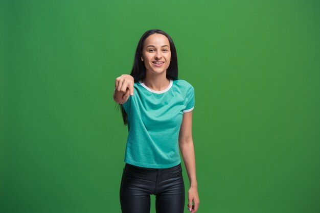 Счастливая деловая женщина указывает на вас и хочет, чтобы вы, половинный портрет крупным планом на зеленом фоне.