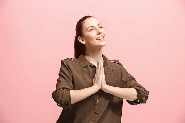 祈り、ピンクの壁に笑みを浮かべて幸せなビジネスの女性。