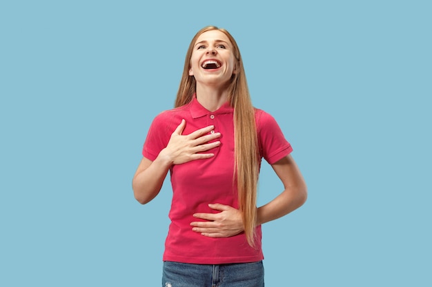 Foto gratuita la donna felice di affari che sta e che sorride contro il fondo blu.