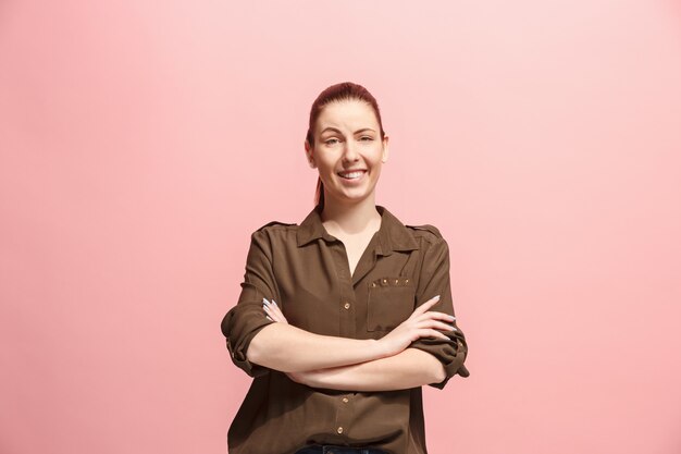 The happy business woman standing and smiling against pink wall.