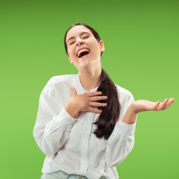 Donna d'affari felice in piedi e sorridente isolato sulla parete verde. bellissimo ritratto femminile a mezzo busto. giovane donna emotiva. le emozioni umane, il concetto di espressione facciale