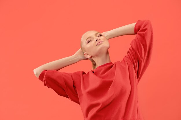 Happy business woman standing, smiling isolated on trendy coral studio background. Beautiful female half-length portrait. Young satisfy woman. Human emotions, facial expression concept