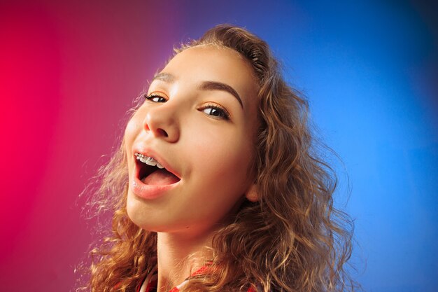 Happy business woman standing and smiling on red and blue studio background. Beautiful female half-length portrait. Young emotional woman. The human emotions, facial expression concept