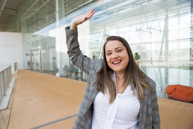 Happy business woman waving with hand outdoors