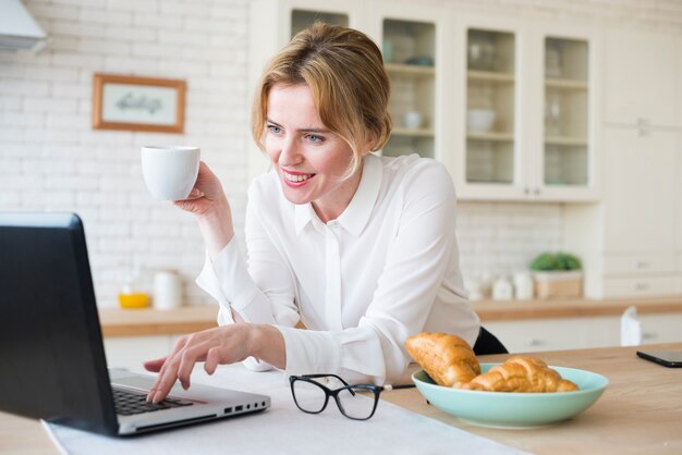 Happy business woman with coffee using laptop