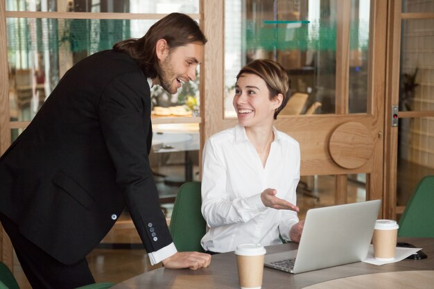 Happy businessman and businesswoman discussing good news online on laptop 