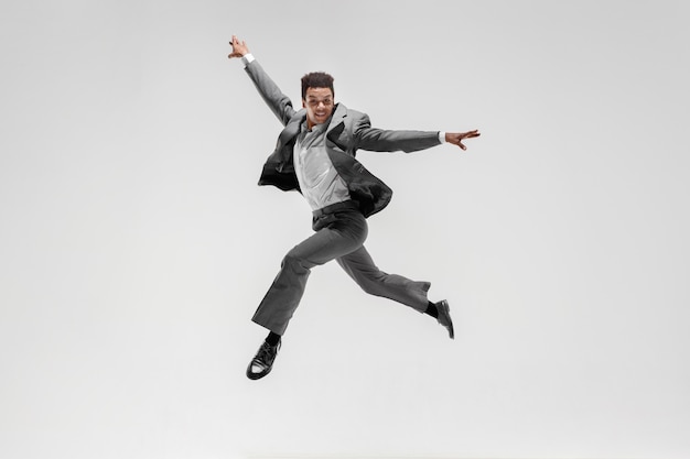 Happy businessman dancing in motion isolated on white studio background. Flexibility and grace in business. Human emotions concept. Office, success, professional, happiness, expression concepts