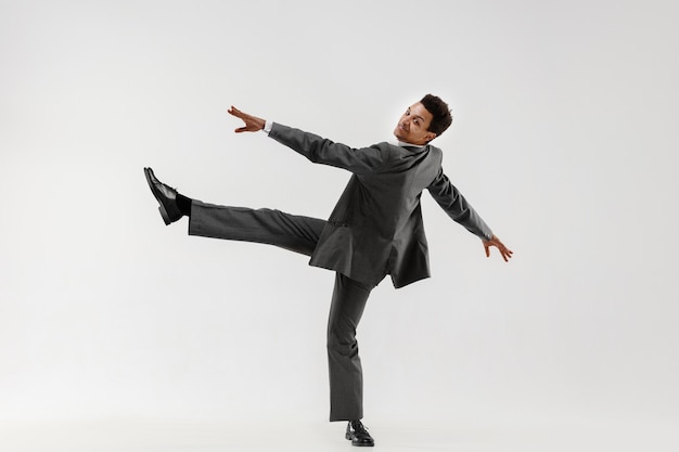 Free photo happy businessman dancing in motion isolated on white studio background. flexibility and grace in business. human emotions concept. office, success, professional, happiness, expression concepts