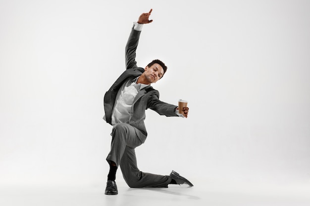 Happy businessman dancing in motion isolated on white studio background. Flexibility and grace in business. Human emotions concept. Office, success, professional, happiness, expression concepts