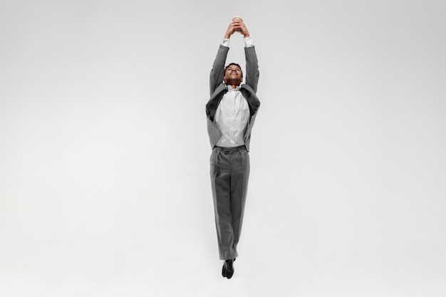 Happy businessman dancing in motion isolated on white studio background. Flexibility and grace in business. Human emotions concept. Office, success, professional, happiness, expression concepts