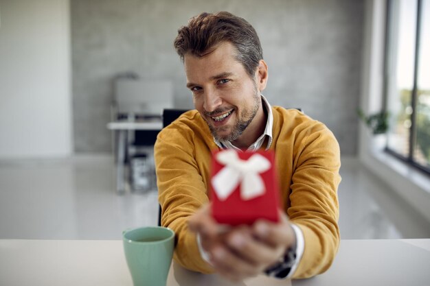 Happy businessman giving a present during video call in the office