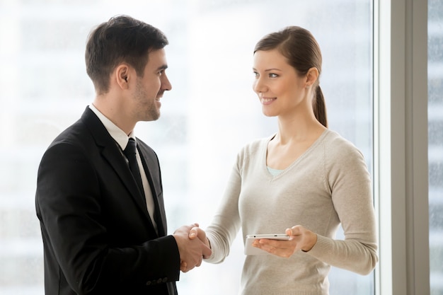 Happy businessman handshaking smiling businesswoman 