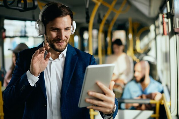 Happy businessman having video call over touchpad in a public transport