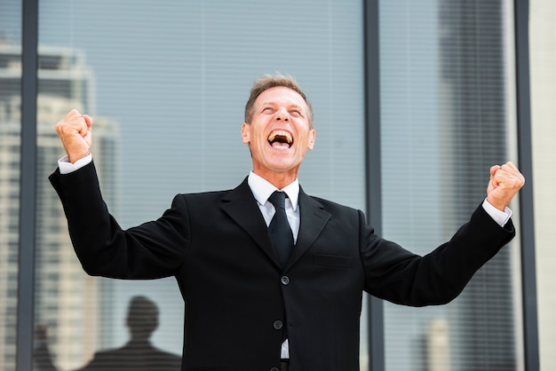 Happy businessman looking up near building