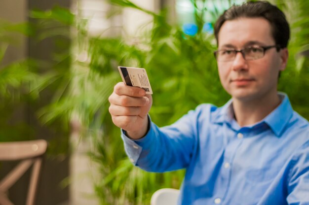 Happy businessman passing his credit card to waiter in cafe. Business man paying with a credit or debit card