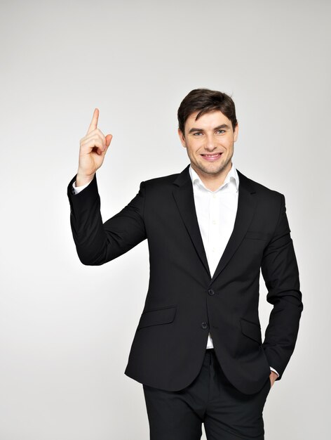 Happy businessman points his finger up in black suit