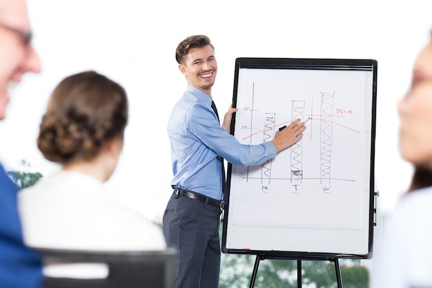 Free photo happy businessman presenting bar chart to colleagues