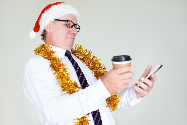 Happy businessman in Santa hat texting message