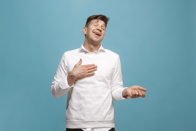 The happy businessman standing and smiling against blue background.