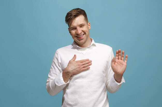 The happy businessman standing and smiling against blue.