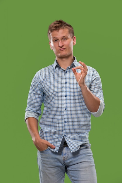 The happy businessman standing and smiling against green wall