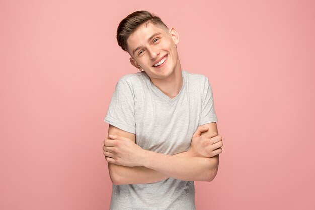 Happy businessman standing and smiling against pink wall.