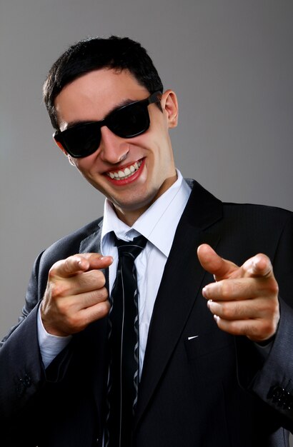 Happy businessman in sunglasses pointing at you