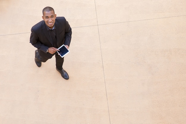 Happy businessman with tablet walking through office hall