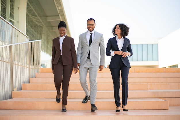 Free photo happy businesspeople walking near office building