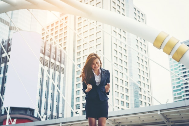 happy businesswoman exults pumping fists ecstatic celebrates success outdoor.