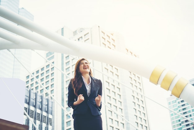 happy businesswoman exults pumping fists ecstatic celebrates success outdoor.