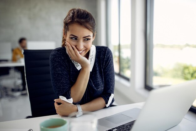 Happy businesswoman having video call over laptop while working in the office