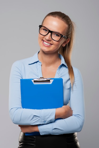 Happy businesswoman holding blue clipboard 
